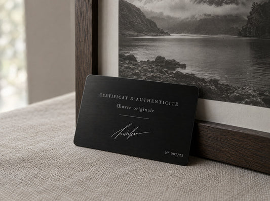 Certificat d'authenticité en aluminium anodisé noir gravé au laser, signé et numéroté 007/25, posé contre un tirage photographique encadré