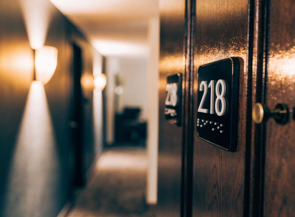 Plaque de chambre braille et relief posée sur une porte dans un couloir d'hôtel